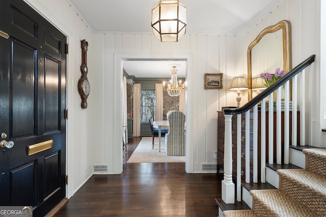 entrance foyer featuring stairs, wood finished floors, visible vents, and a chandelier