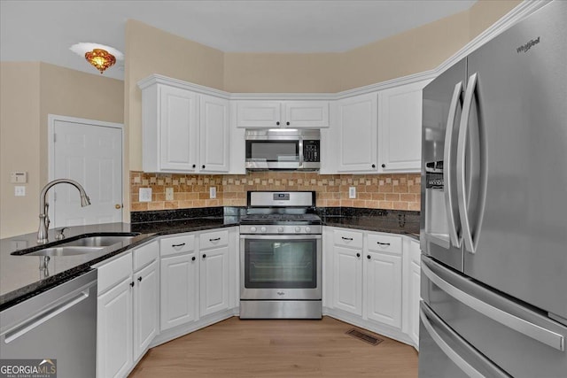 kitchen with appliances with stainless steel finishes, a sink, visible vents, and white cabinets