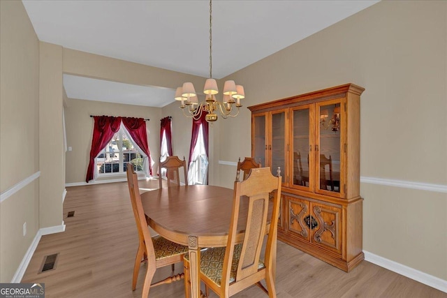 dining area featuring light wood-type flooring, visible vents, a notable chandelier, and baseboards