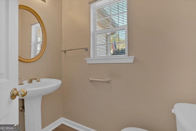 bathroom with baseboards, a sink, and toilet