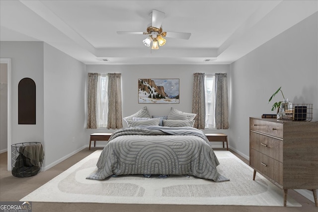 bedroom featuring visible vents, a tray ceiling, and baseboards