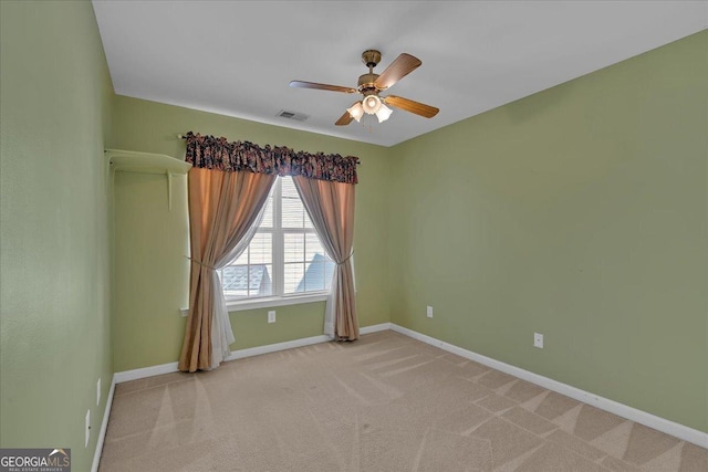 spare room with light carpet, ceiling fan, visible vents, and baseboards