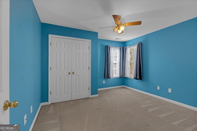 unfurnished bedroom featuring a closet, visible vents, carpet flooring, ceiling fan, and baseboards