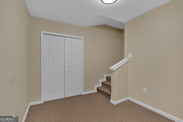 interior space with carpet, a closet, lofted ceiling, and baseboards