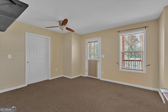 interior space featuring ceiling fan, dark colored carpet, and baseboards