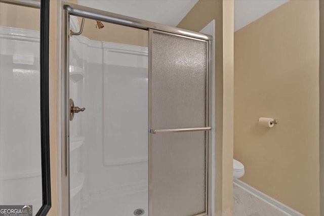 full bath featuring toilet, marble finish floor, a shower stall, and baseboards