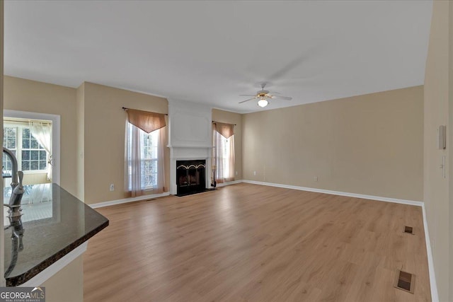 unfurnished living room with a large fireplace, plenty of natural light, and light wood finished floors