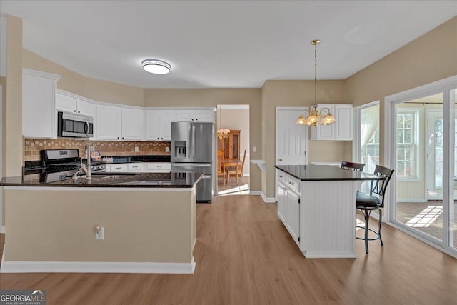 kitchen with appliances with stainless steel finishes, white cabinetry, light wood-style floors, and tasteful backsplash