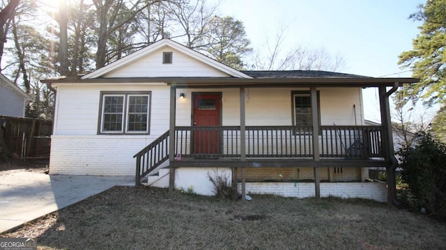 view of front of home with fence, a porch, and brick siding