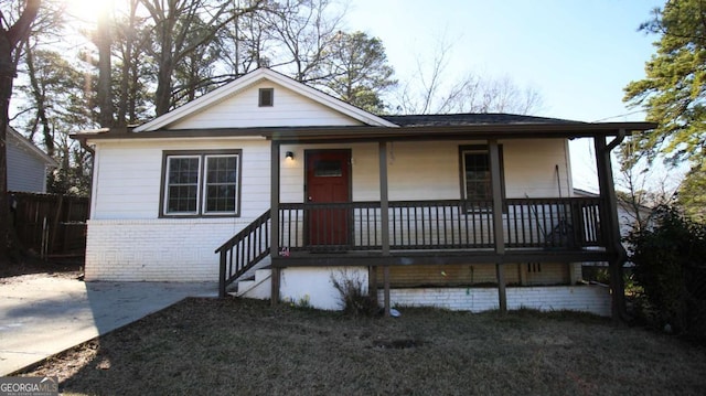 view of front facade with covered porch, fence, and brick siding