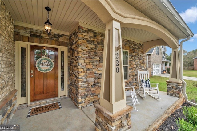 entrance to property featuring covered porch, stone siding, and brick siding