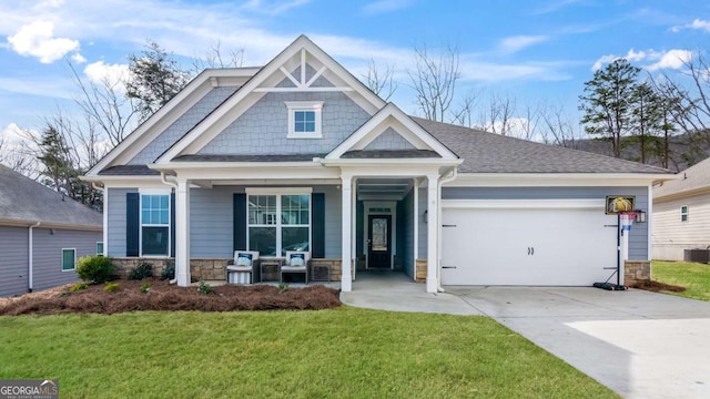 craftsman house with a porch, a garage, stone siding, concrete driveway, and a front yard