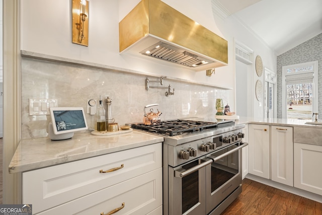 kitchen featuring range with two ovens, dark wood-style flooring, white cabinetry, vaulted ceiling, and wall chimney exhaust hood