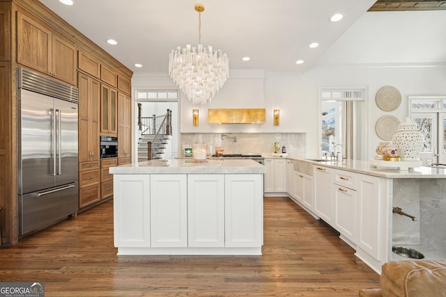 kitchen with stainless steel built in fridge, custom range hood, dark wood-style floors, and decorative backsplash