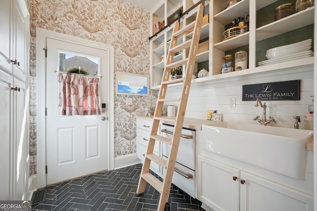 interior space featuring wallpapered walls, visible vents, baseboards, a sink, and brick patterned floor