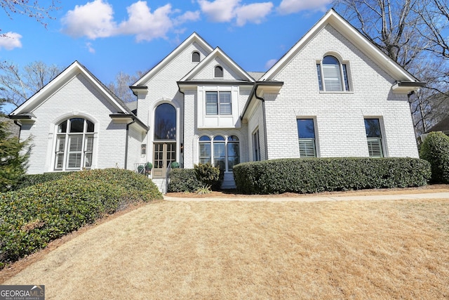 view of front facade with brick siding and a front lawn