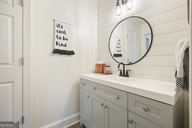 bathroom featuring wood walls, vanity, and baseboards