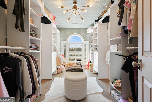 spacious closet featuring a chandelier, visible vents, and light wood finished floors