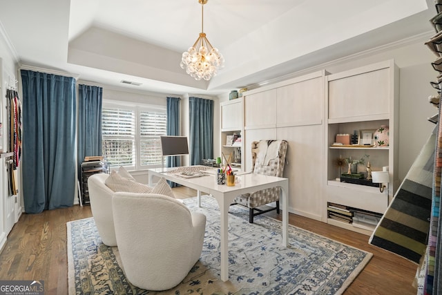 dining room featuring wood finished floors, a raised ceiling, and visible vents