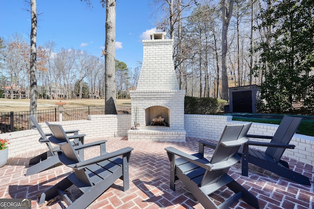 view of patio / terrace featuring an outdoor brick fireplace and fence