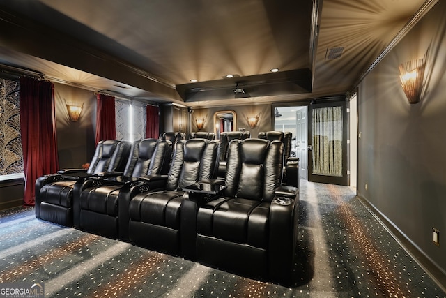 carpeted home theater featuring baseboards, visible vents, a raised ceiling, and crown molding