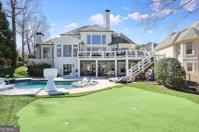 back of property with stairway, an outdoor pool, a patio, and a chimney