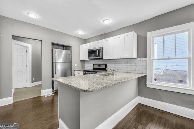 2006 Conrad Ave SE, Atlanta, GA 30315 - kitchen with dark wood-style flooring, baseboards, a peninsula, stainless steel appliances, and a sink