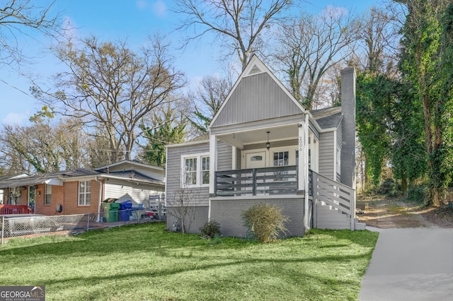 view of front of home featuring covered porch, a front lawn, a chimney, and fence