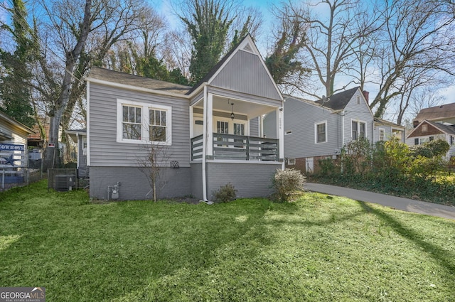 bungalow-style home with covered porch, fence, a front lawn, and central air condition unit