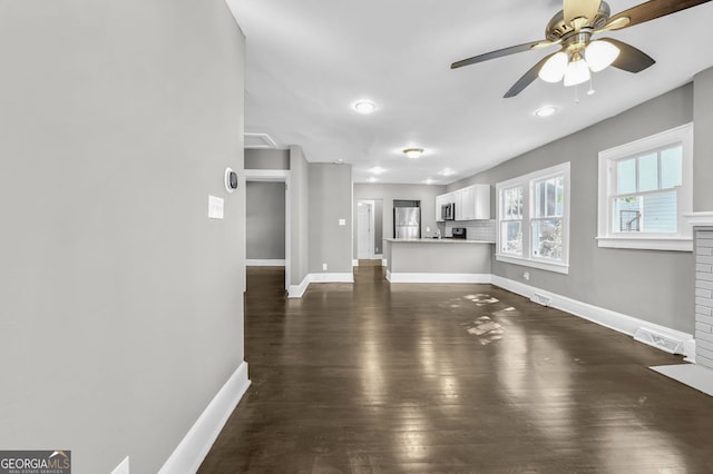 unfurnished living room featuring visible vents, baseboards, ceiling fan, and dark wood-style flooring