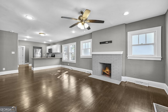 2006 Conrad Ave SE, Atlanta, GA 30315 - unfurnished living room featuring visible vents, baseboards, ceiling fan, a fireplace, and dark wood-type flooring