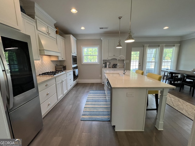 kitchen with stainless steel appliances, white cabinets, premium range hood, and visible vents