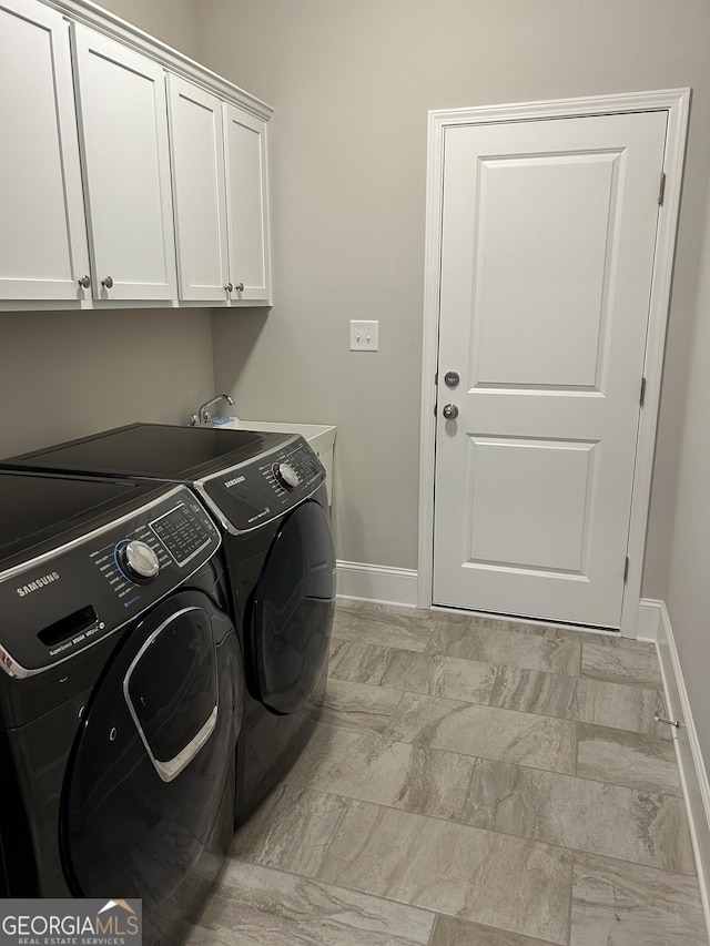 laundry area with cabinet space, a sink, baseboards, and separate washer and dryer