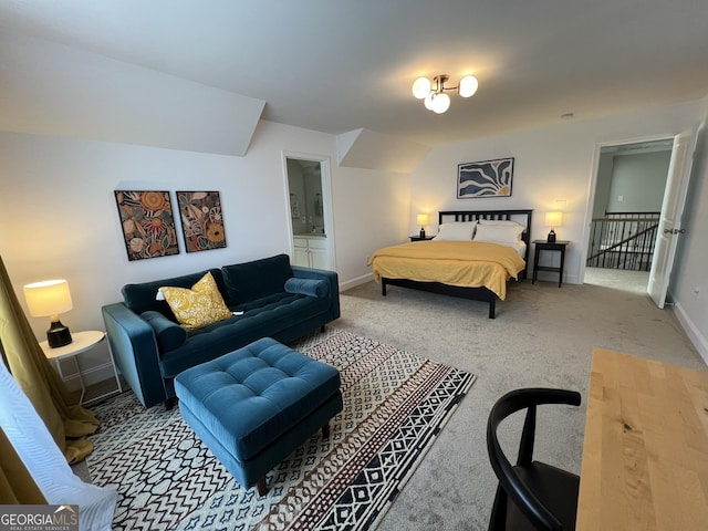 carpeted bedroom featuring ensuite bath and baseboards