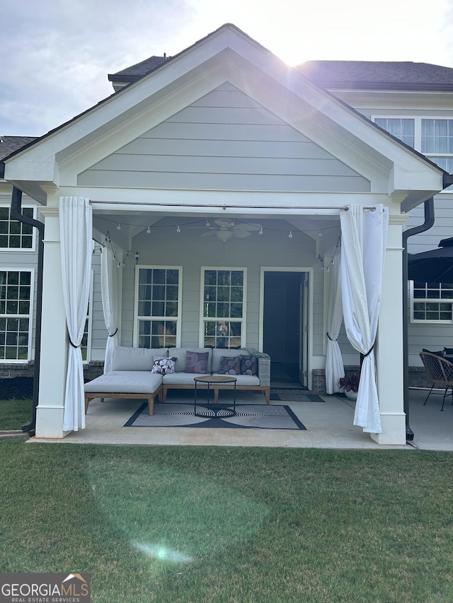 back of property with a patio area, outdoor lounge area, a lawn, and ceiling fan