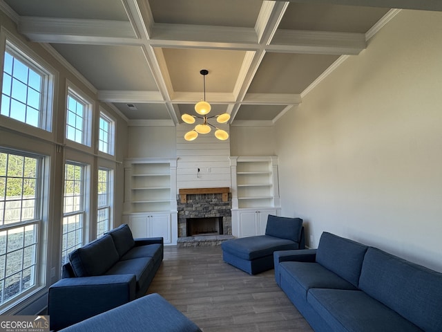 living room featuring coffered ceiling, beamed ceiling, wood finished floors, a stone fireplace, and a chandelier