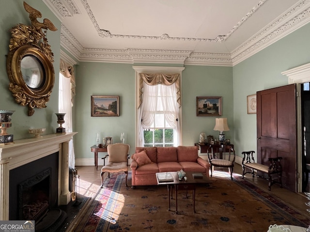 living room featuring crown molding, a fireplace, baseboards, and wood finished floors