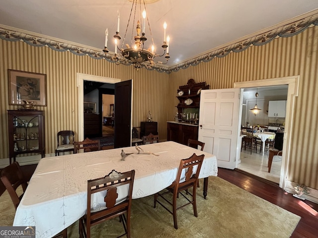 dining space featuring a chandelier, wood finished floors, and wallpapered walls