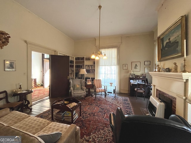 living room featuring wood finished floors, heating unit, vaulted ceiling, a fireplace, and a chandelier