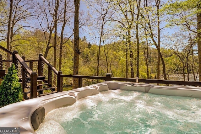 wooden terrace featuring a hot tub and a wooded view