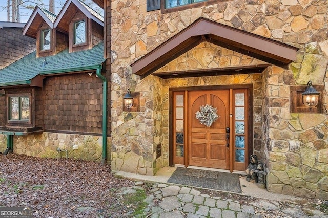 property entrance with stone siding and a shingled roof