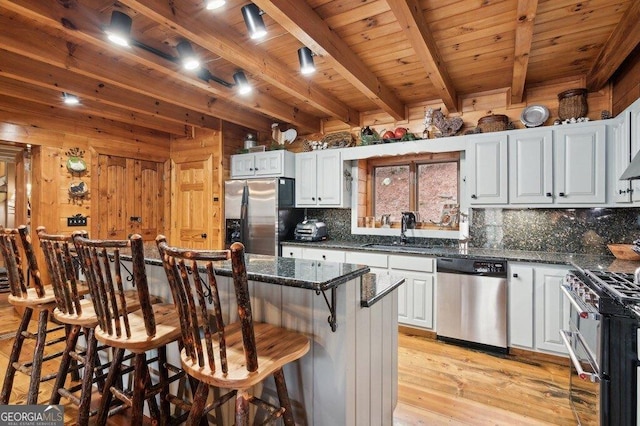 kitchen featuring appliances with stainless steel finishes, wooden ceiling, a sink, and wooden walls