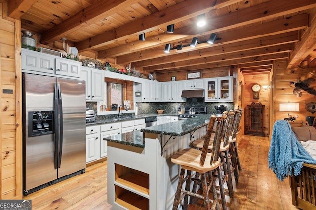 kitchen with under cabinet range hood, appliances with stainless steel finishes, a sink, and beamed ceiling