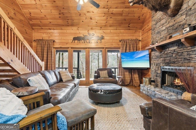 living area featuring wood ceiling, wooden walls, wood finished floors, and a stone fireplace