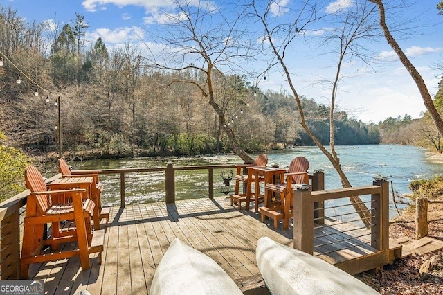 wooden terrace featuring a water view and a view of trees