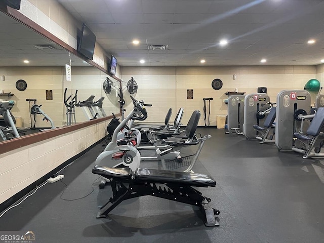 workout area featuring concrete block wall, visible vents, and recessed lighting