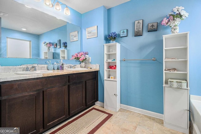 full bath featuring double vanity, a sink, baseboards, and a bath