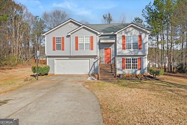 split foyer home with an attached garage, concrete driveway, and a front yard