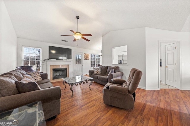 living room featuring lofted ceiling, visible vents, a high end fireplace, ceiling fan, and wood finished floors