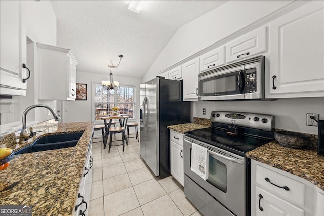 kitchen featuring light tile patterned floors, lofted ceiling, appliances with stainless steel finishes, white cabinets, and a sink